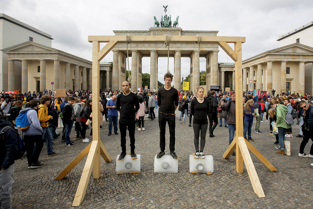 Three persons stand on ice blocks under gallows to protest against the climate policy prior to a 'Friday for Future' climate protest in front of the Brandenburg Gate in Berlin, Germany